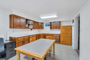 Kitchen featuring open shelves, brown cabinets, light countertops, and ornamental molding