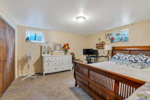 Carpeted bedroom featuring a textured ceiling and a closet