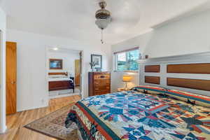 Bedroom featuring wood finished floors, ensuite bathroom, and a ceiling fan