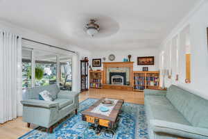 Living room with ornamental molding, wood finished floors, and ceiling fan