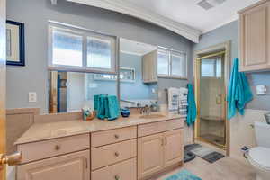 Full bathroom with crown molding, a stall shower, and double vanity