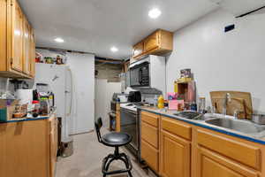 Kitchen featuring concrete floors, electric stove, black microwave, and freestanding refrigerator