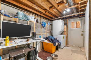 Unfinished basement featuring stacked washing machine and dryer