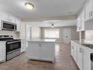 Kitchen featuring appliances with stainless steel finishes, a textured ceiling, white cabinets, light countertops, and a ceiling fan