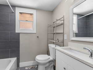 Bathroom with a textured ceiling, vanity, and washtub / shower combination