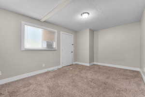 Unfurnished room featuring a textured ceiling and carpet