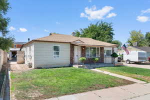 Bungalow featuring a front yard, roof with shingles, stone siding, and a chimney