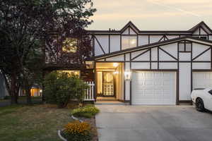 English style home with concrete driveway, a garage, stucco siding, a front yard, and brick siding
