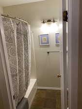 Full bathroom featuring shower / bath combo with shower curtain and stone finish flooring