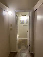 Hall featuring baseboards and stone finish floors