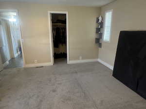 Unfurnished bedroom with carpet flooring and a walk in closet