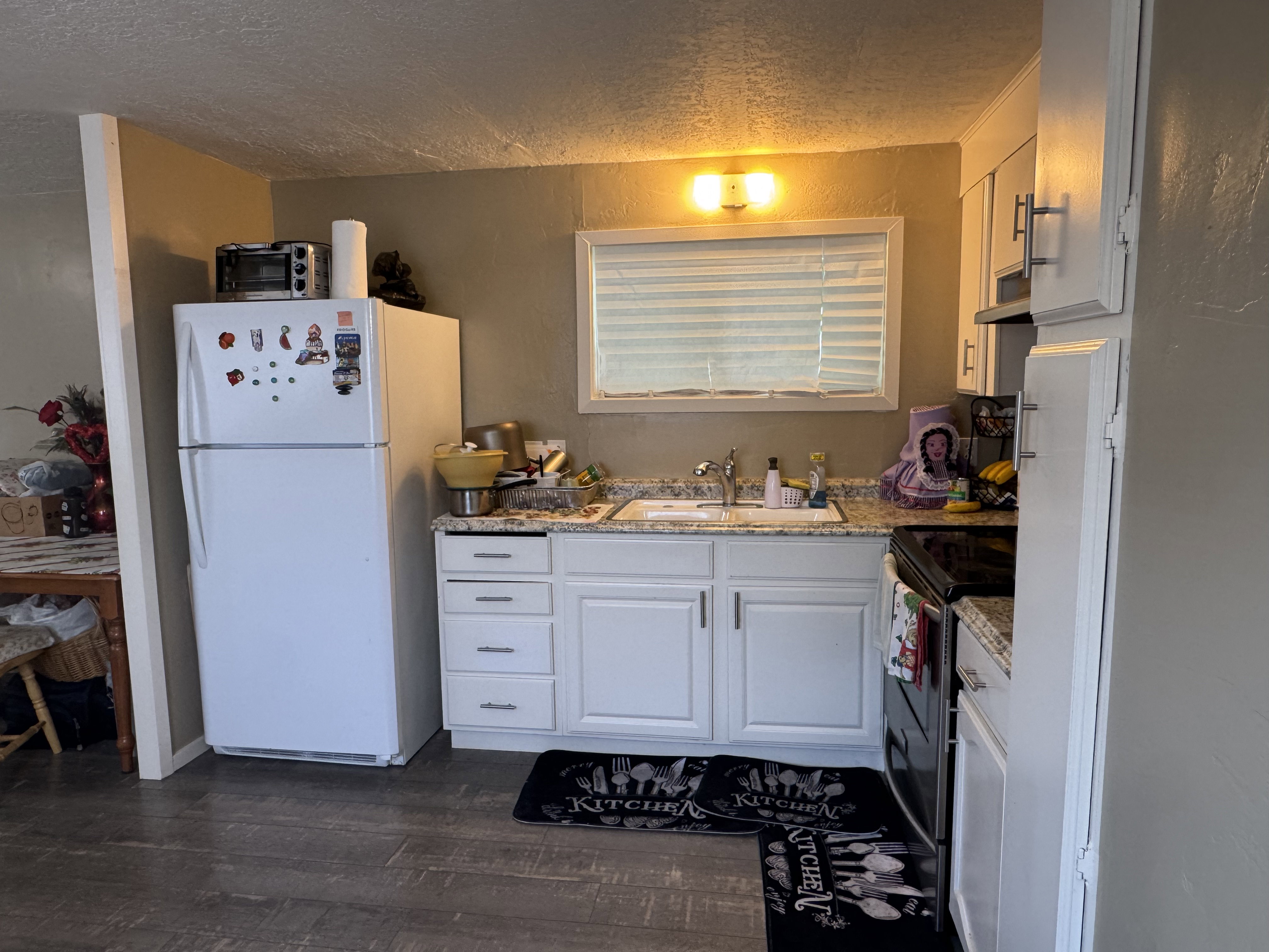 Kitchen with a textured ceiling, freestanding refrigerator, white cabinetry, stainless steel electric range, and dark wood-style floors