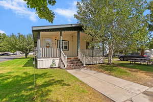 View of front of home featuring covered porch, a front yard, and stucco siding