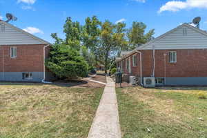 View of property exterior with brick siding and a yard