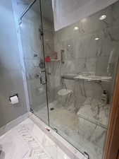 Full bathroom with a marble finish shower and toilet