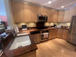 Kitchen featuring stainless steel appliances, dark stone countertops, light wood-style flooring, modern cabinets, and recessed lighting