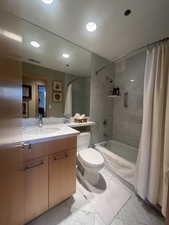 Bathroom featuring shower / tub combo, vanity, marble look tiles, and recessed lighting