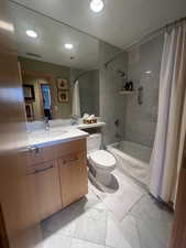Full bathroom with shower / bath combo with shower curtain, vanity, recessed lighting, and marble look tiles