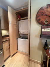 Washroom featuring stacked washer and clothes dryer and light wood-type flooring