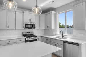 Kitchen with appliances with stainless steel finishes, light countertops, hanging light fixtures, decorative backsplash, and recessed lighting