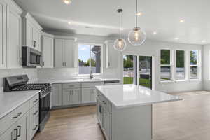 Kitchen with stainless steel appliances, light countertops, recessed lighting, a center island, and light wood-style flooring