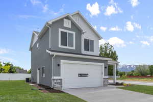 Traditional-style house featuring a garage, stone siding, driveway, and stucco siding