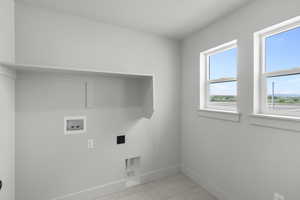 Washroom with hookup for an electric dryer, hookup for a washing machine, and light tile patterned floors