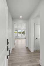 Hallway with light wood finished floors and recessed lighting