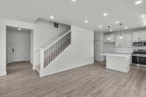 Kitchen featuring appliances with stainless steel finishes, recessed lighting, light countertops, a center island, and light wood-type flooring