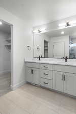 Full bathroom featuring double vanity, a walk in closet, tile patterned floors, and recessed lighting