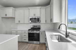 Kitchen featuring appliances with stainless steel finishes, light wood-style flooring, light countertops, and decorative backsplash