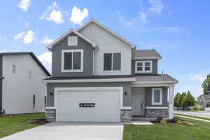 View of front of house with driveway, a front yard, a garage, and stone siding