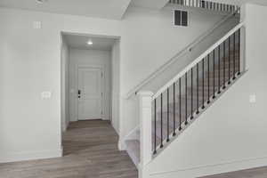 Stairway featuring wood finished floors and recessed lighting