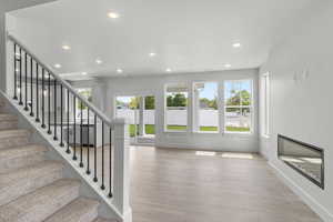 Stairway featuring healthy amount of natural light, wood finished floors, recessed lighting, and a glass covered fireplace