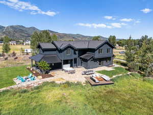 Rear view of property with a patio, a mountain view, and a yard