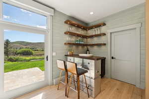 Indoor dry bar with light wood finished floors and butcher block countertops