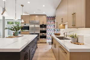 Kitchen featuring light stone countertops, decorative light fixtures, light wood finished floors, recessed lighting, and appliances with stainless steel finishes