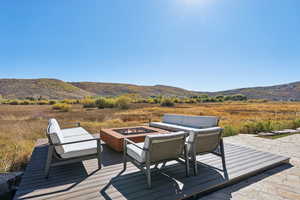 Deck featuring a mountain view, an outdoor living space with a fire pit, and a patio