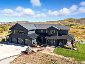 Modern farmhouse featuring concrete driveway, an attached garage, a porch, and a mountain view