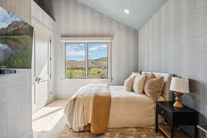 Bedroom with wallpapered walls, lofted ceiling, and recessed lighting