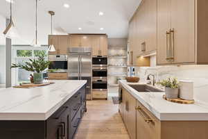 Kitchen with light stone countertops, hanging light fixtures, stainless steel appliances, recessed lighting, and light wood finished floors