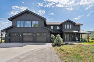 View of front facade with concrete driveway, a garage, board and batten siding, a standing seam roof, and a porch