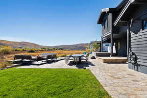 View of grassy yard featuring a patio area, a mountain view, an outdoor hangout area, and a balcony