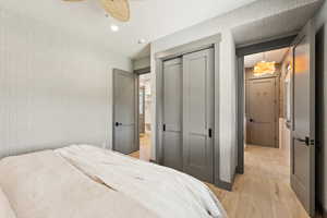 Bedroom with wallpapered walls, light wood finished floors, a closet, and recessed lighting