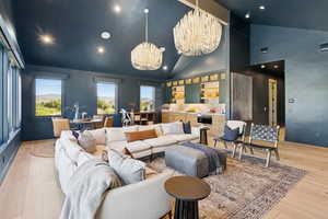 Living room with recessed lighting, light wood-style flooring, a chandelier, and high vaulted ceiling