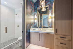 Full bath with a stall shower, vanity, and wallpapered walls