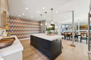 Kitchen with a breakfast bar, hanging light fixtures, recessed lighting, light wood-style flooring, and a center island
