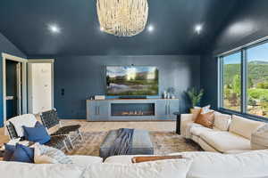 Living room with vaulted ceiling, wood finished floors, a glass covered fireplace, and recessed lighting