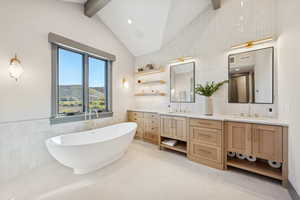 Bathroom with tile walls, a freestanding bath, double vanity, light tile patterned floors, and wainscoting