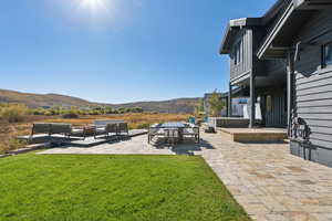 Patio / terrace featuring a patio area, an outdoor hangout area, a mountain view, and a lawn